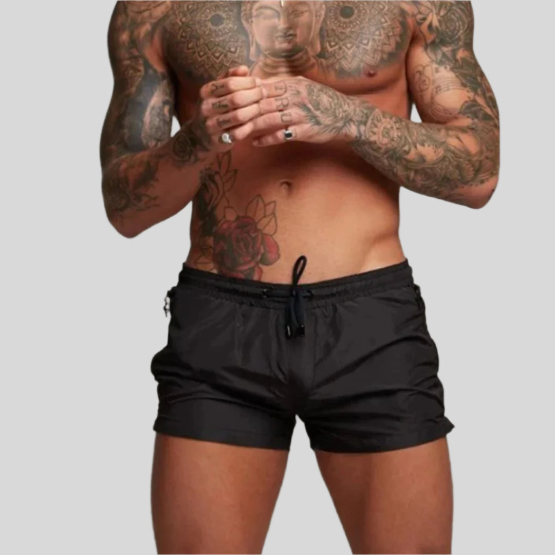 Man wearing quick-dry men's swim shorts on beach. Perfect for resort wear & summer activities.