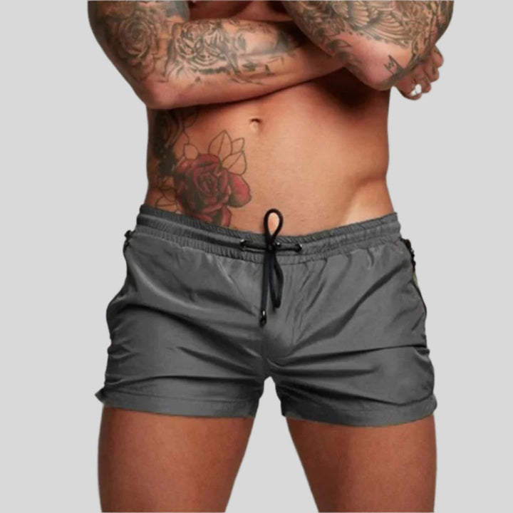 Stylish men's drawstring swim shorts with zip pockets for versatile summer fashion & beachwear.