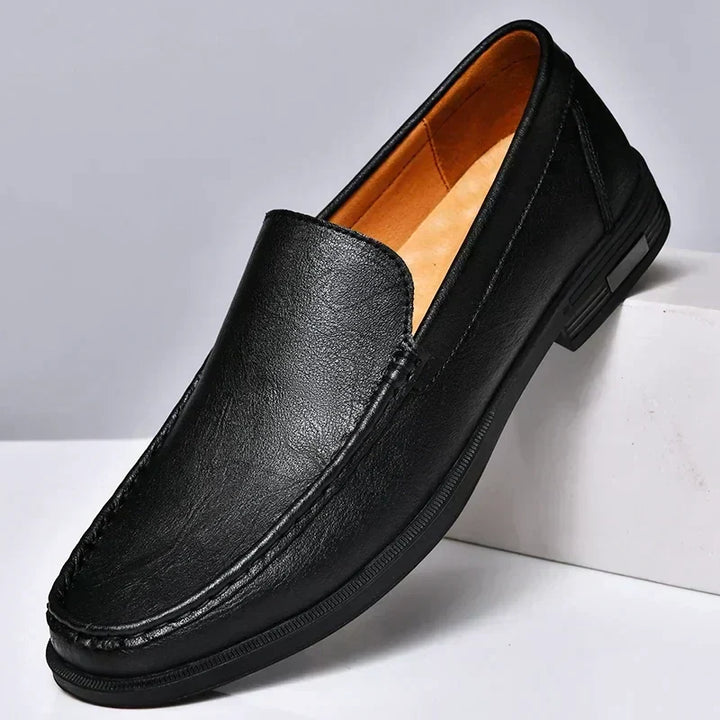 Close-up of sophisticated men's black leather slip-on loafers, highlighting rich texture and quality craftsmanship. Dress shoes.