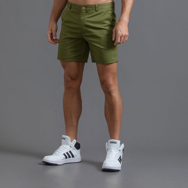 Stack of men's knee-length chino shorts in various summer colors, essential for warm weather wardrobe.