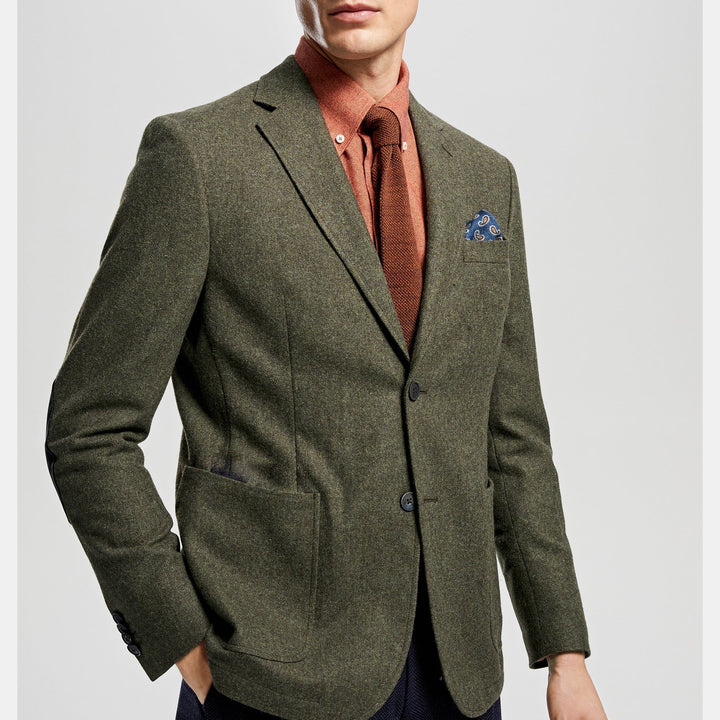 Close-up of a tailored olive green men's suit jacket. Three-piece formal wear, ideal for weddings.