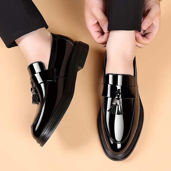 Close-up of men's elegant polished black leather penny loafers with stylish tassels.