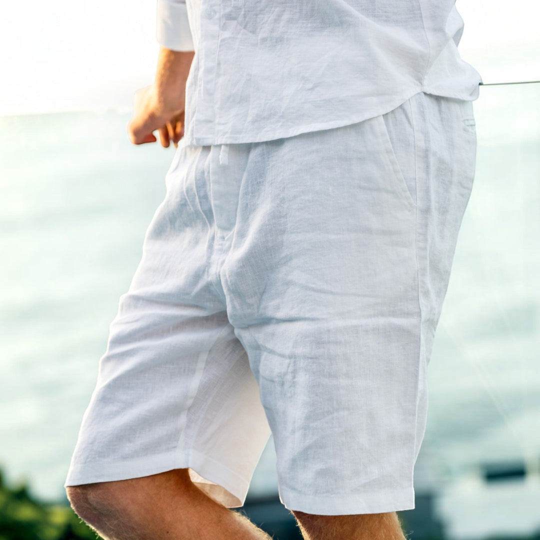 Man walking on beach wearing stylish men's relaxed fit shorts, enjoying a warm summer day.