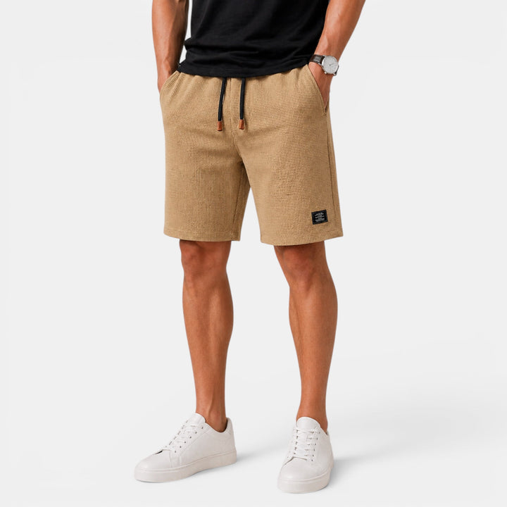 Model in comfortable men's relaxed fit summer shorts. Ideal beachwear or vacation outfit. Elastic waist.