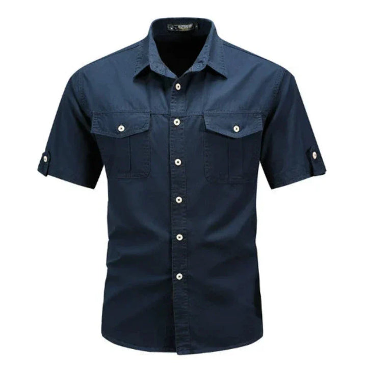 Stylish man wearing a blue short sleeve cargo shirt, a comfortable utility button-up perfect for summer casual fashion.