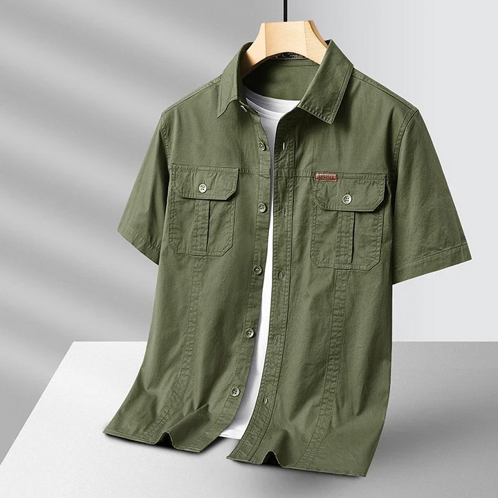 Men's short sleeve utility button-up shirt in light blue, perfect for summer casual wear and travel, with chest pockets.
