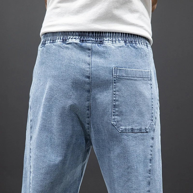 Tapered fit men's stretch denim jogger trousers, comfortable elastic waist casual pants.