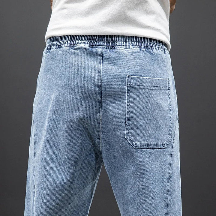 Tapered fit men's stretch denim jogger trousers, comfortable elastic waist casual pants.