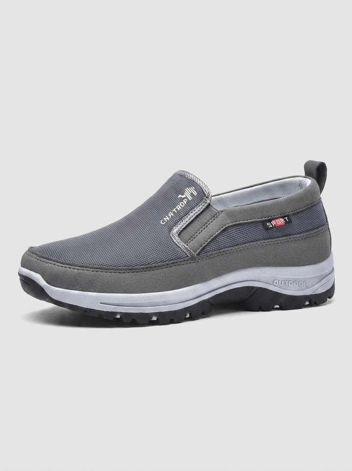Men's feet in black waterproof orthopedic slip-on comfort sneakers, perfect for casual everyday footwear.