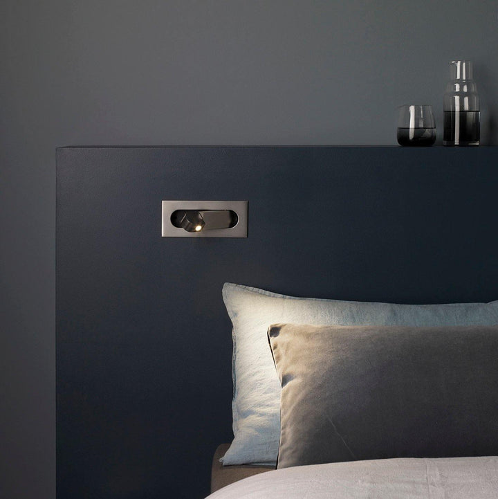 Adjustable LED reading lamp in matte black finish, wall-mounted for bedroom convenience.