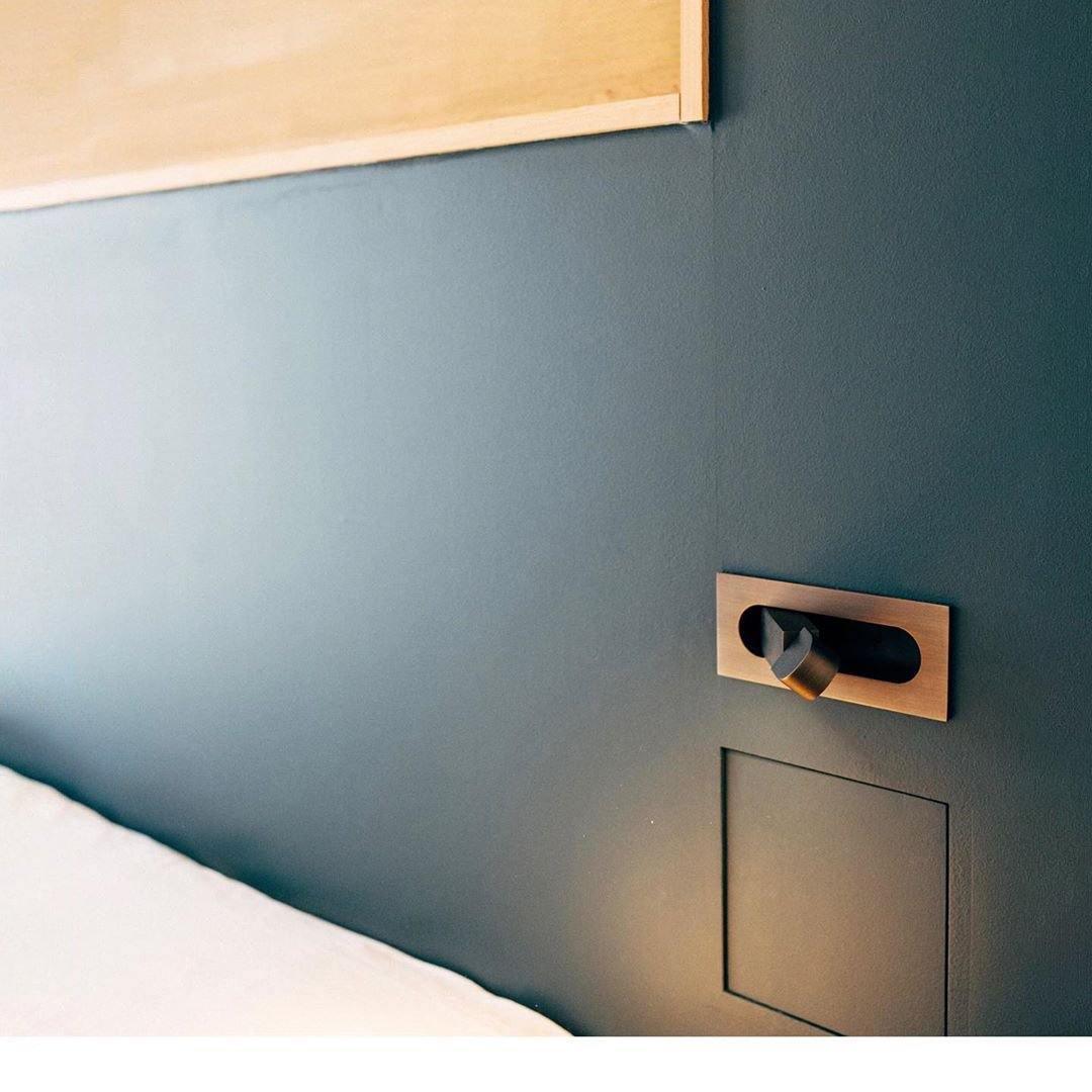 Sleek contemporary LED bedside lamp, wall-mounted with adjustable arm; white finish.