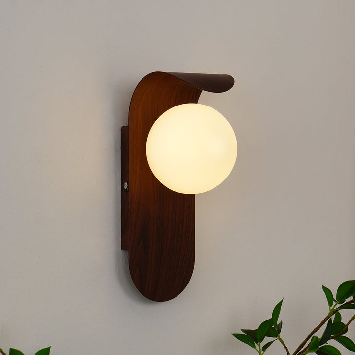 Indoor wood effect LED wall lamp with a frosted opal glass globe, creating soft light.
