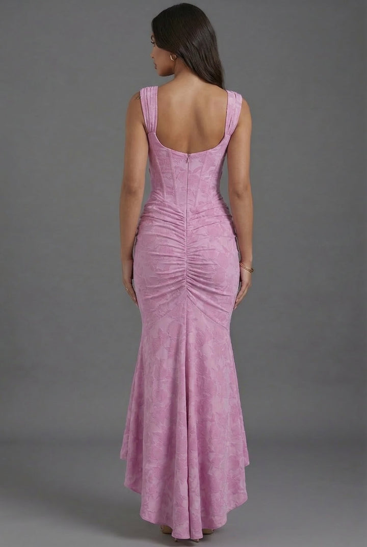 Stunning pink women's wedding guest maxi dress with a corset bodice, ruched skirt, square neckline, and open back.
