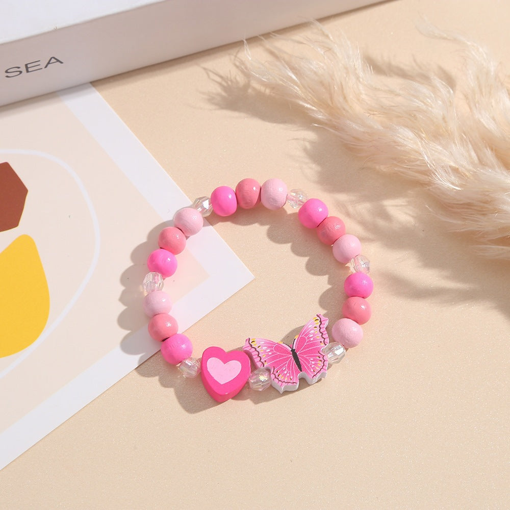 Close-up of a playful pink wooden bead charm bracelet with detailed heart & butterfly charms for women/girls.