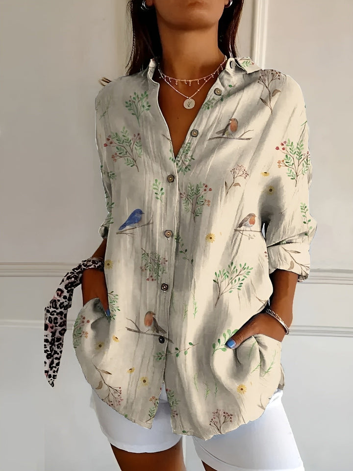 Woman modeling a chic plus size blue floral print long sleeve button-up shirt, elegant and casual.