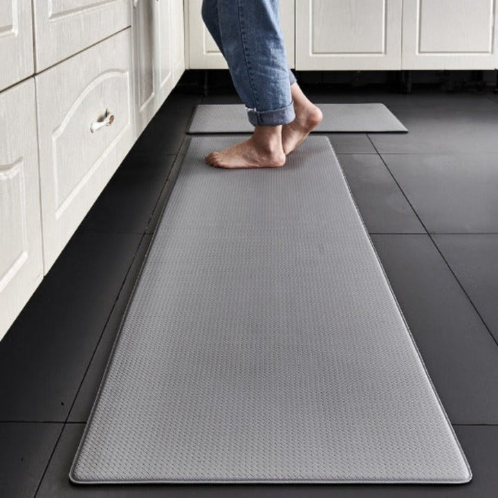 Red cushioned anti-fatigue kitchen mat provides comfort & support for standing, ideal for home kitchen decor.