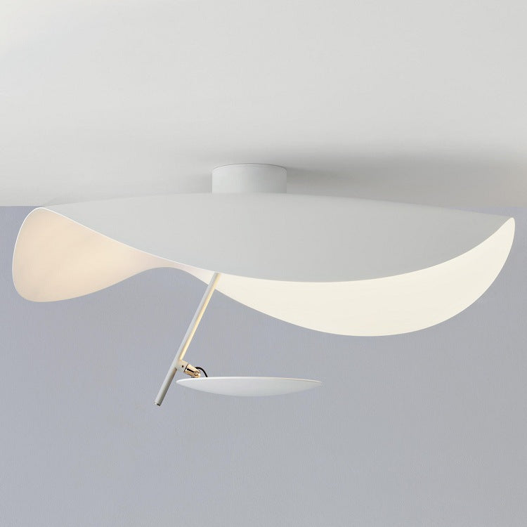 Gold modern leaf light, casting intricate shadows, enhancing a contemporary living room.