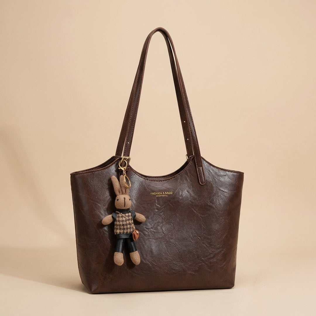 Front view of a chic women's vegan leather tote bag, featuring a cute bunny charm. Great for everyday wear.