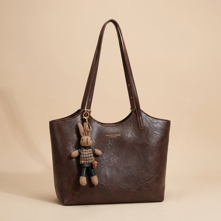Front view of a chic women's vegan leather tote bag, featuring a cute bunny charm. Great for everyday wear.