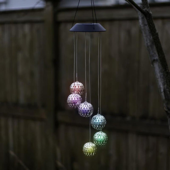 Metal solar wind chime orb with color-changing LED lights. Adds vibrant ambiance to any garden or patio decor.