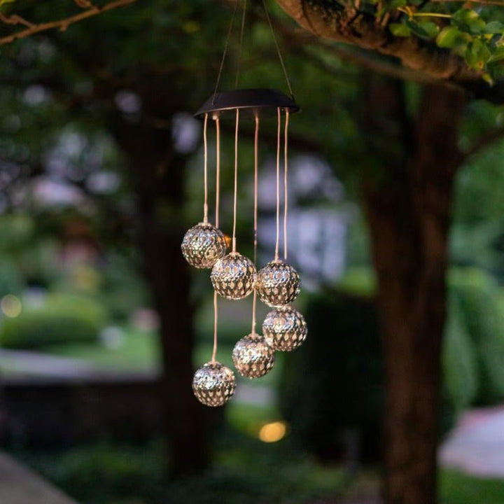 Solar powered LED wind chime orb, provides soothing color-changing light for tranquil garden and patio ambiance.