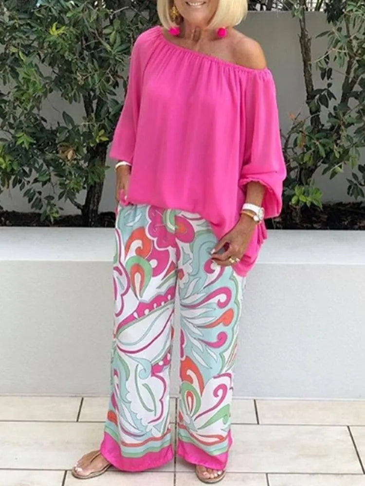 Stylish pink off-shoulder two-piece set for women. Features lantern sleeve top & wide-leg pants for a boho summer look.