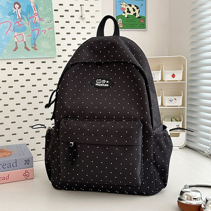 Woman wearing a chic black polka dot backpack, ideal for travel or daily commutes. Fashionable & organized design.