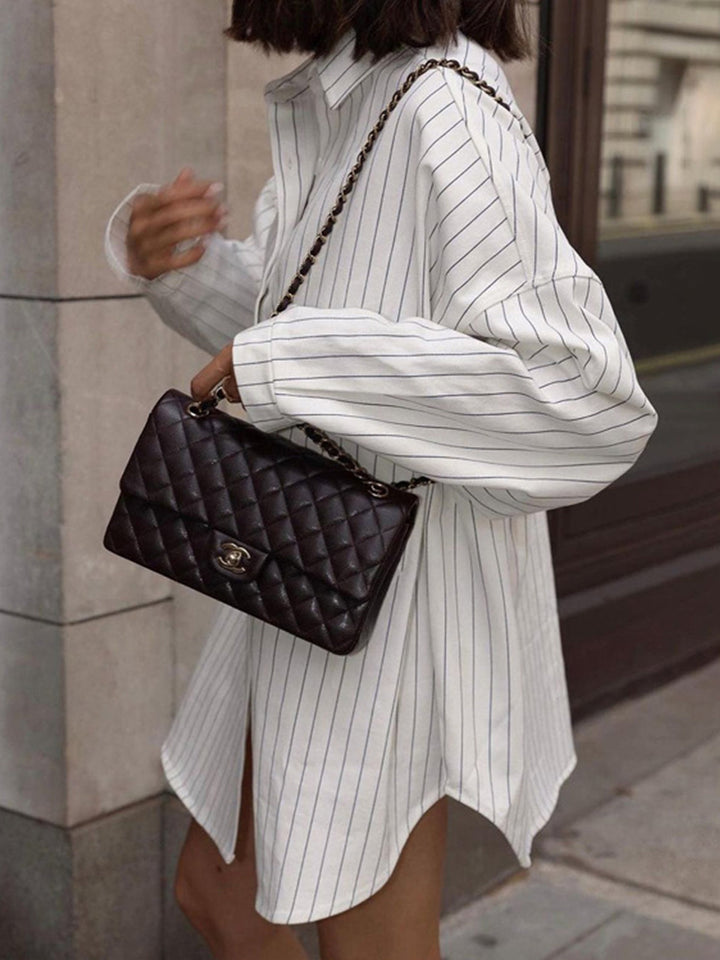 Modern women's white striped oversized shirt dress, featuring a relaxed button-down fit for effortless style.