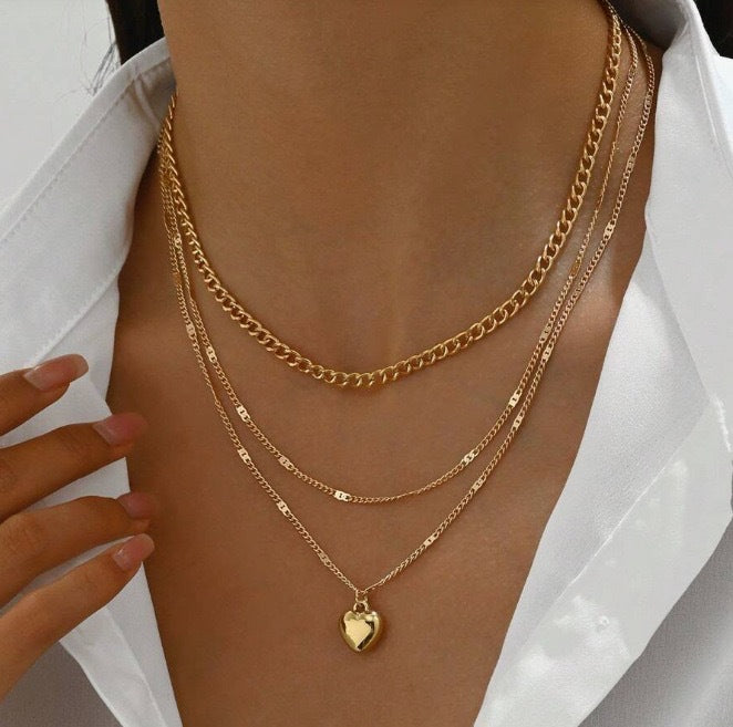 Triple layered gold chain necklace with a delicate heart pendant, perfect women's fashion jewelry.