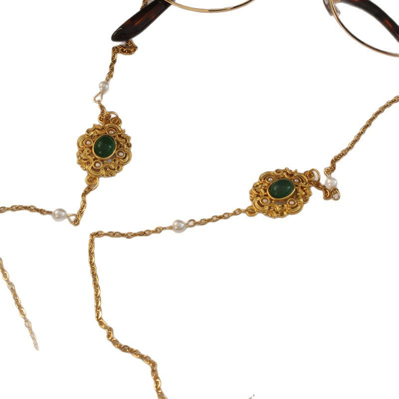 Luxurious gold-tone glasses chain featuring delicate white pearls and vibrant green stones. Unisex fashion eyewear holder.