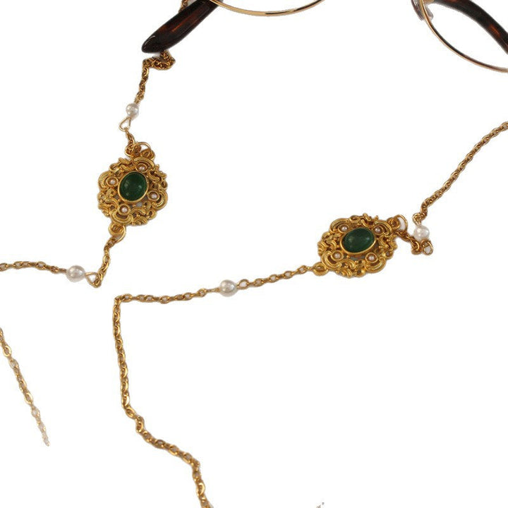 Luxurious gold-tone glasses chain featuring delicate white pearls and vibrant green stones. Unisex fashion eyewear holder.