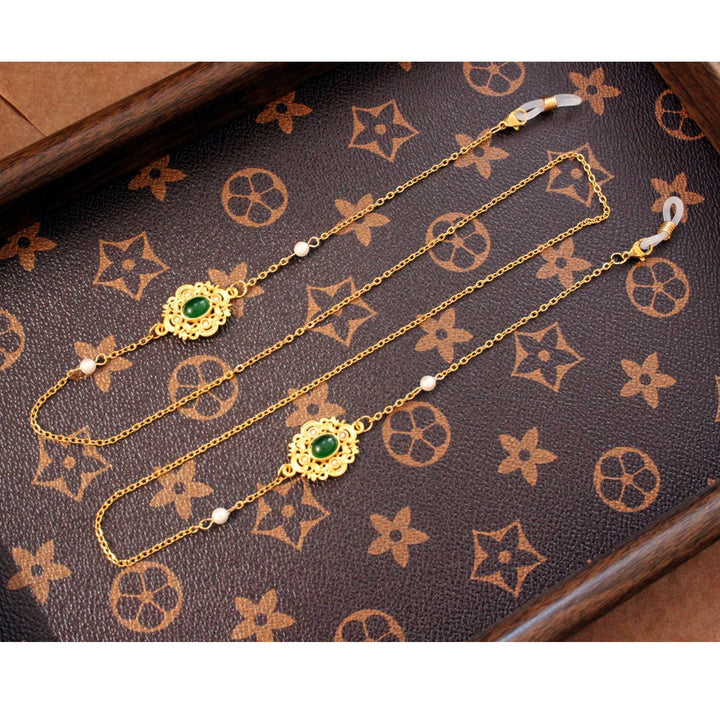 Elegant gold glasses chain adorned with luminous pearls and faceted green stones. A chic unisex eyewear holder accessory.