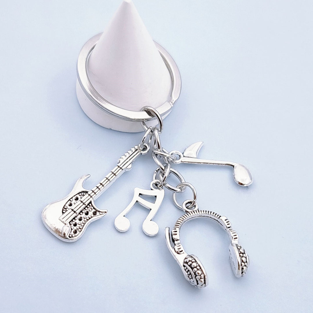Stylish silver musical instrument keychain charm with guitar, headphones, & music notes, ideal unisex gift.