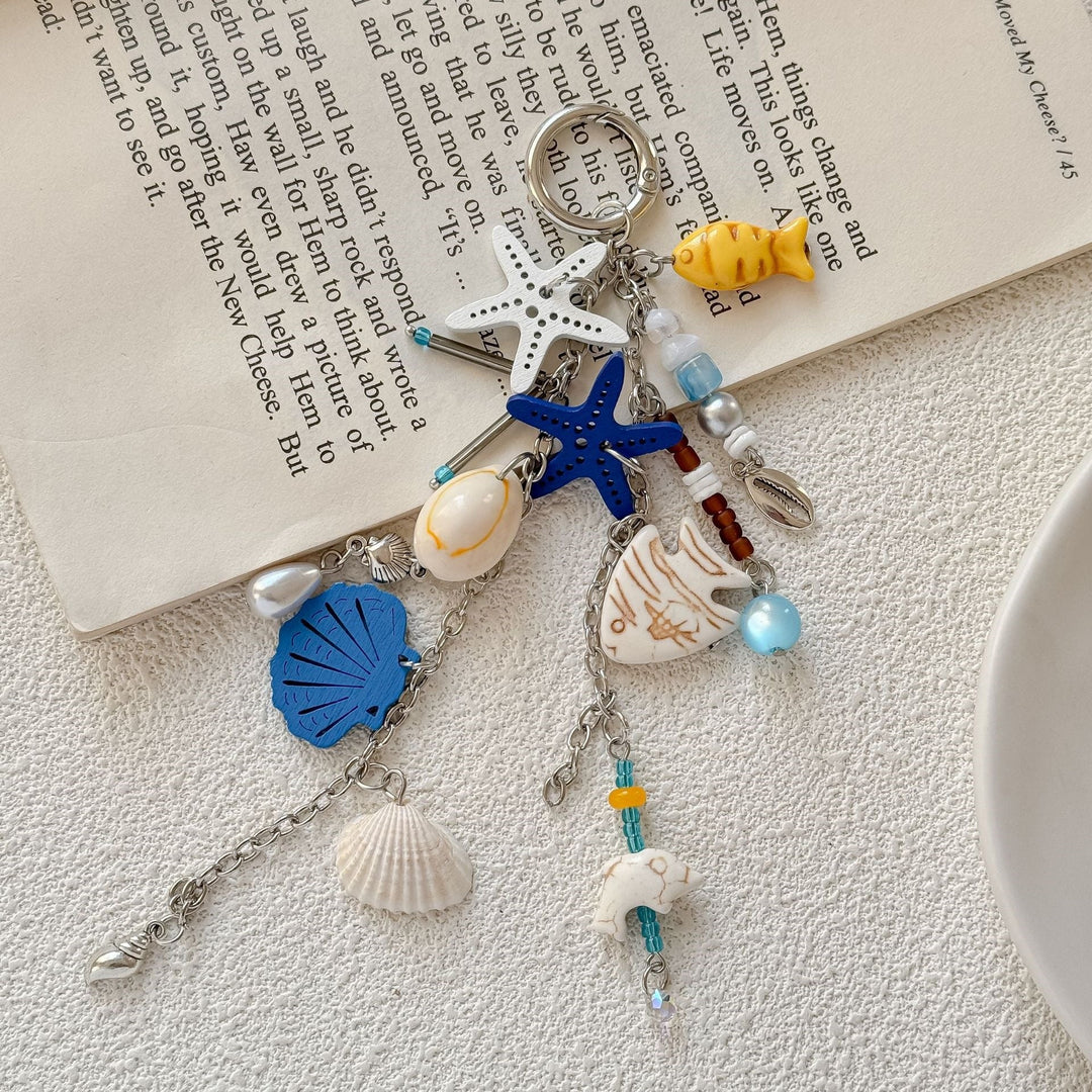 Ocean-themed keychain featuring detailed nautical charms like anchor, compass, & seashell, blue accents.