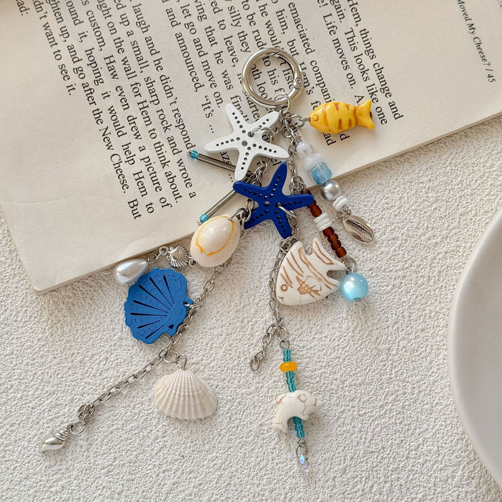 Ocean-themed keychain featuring detailed nautical charms like anchor, compass, & seashell, blue accents.