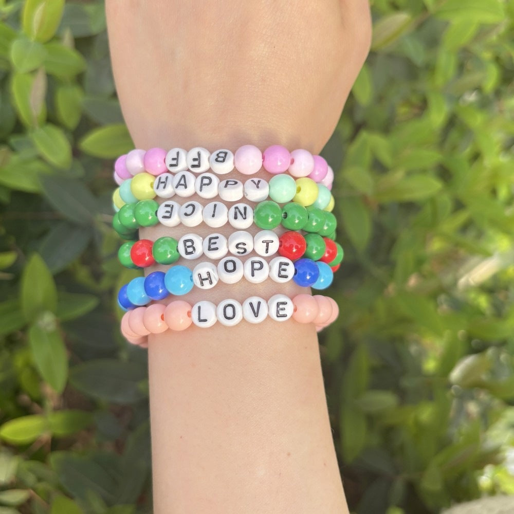Unisex pastel bead friendship bracelet with white 'LOVE' letters. A charming beaded stretch accessory.