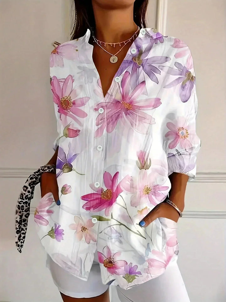 Close-up of vibrant artistic floral print on women's loose button-front blouse with long sleeves.