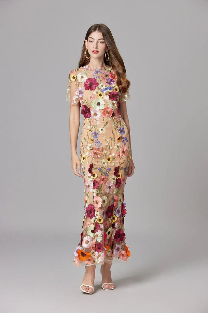 Woman twirling in a flowing 3D floral appliqué sleeveless maxi dress, elegant party wear.