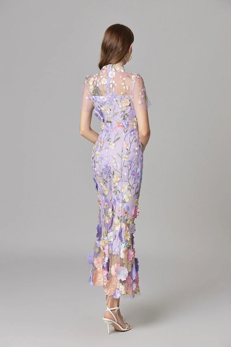 Side profile of a woman wearing an elegant 3D floral appliqué sleeveless maxi dress.
