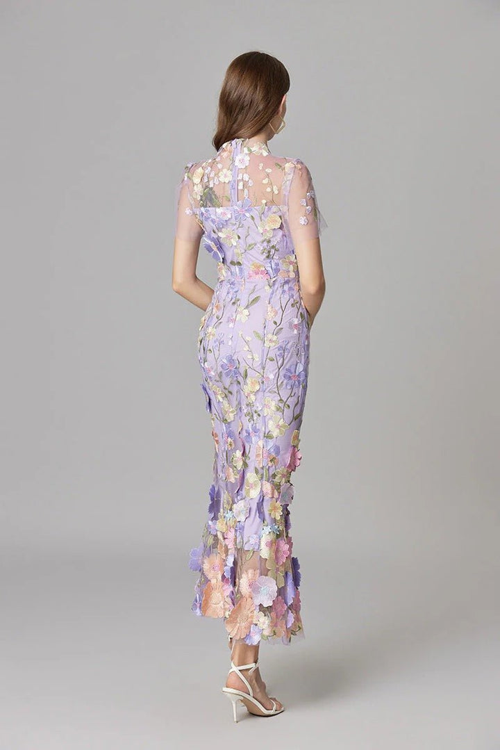 Side profile of a woman wearing an elegant 3D floral appliqué sleeveless maxi dress.