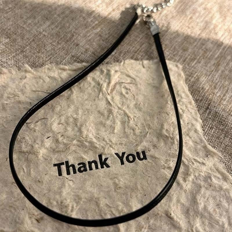 Close-up of a women's black leather choker necklace, showing adjustable buckle and smooth leather texture.