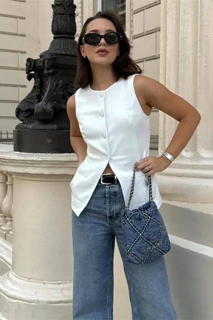 Fashionable women's asymmetric sleeveless top, tailored waistcoat style with a sleek button front. Modern layering.