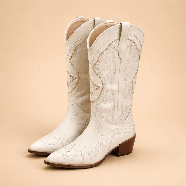 Women's beige knee-high cowboy boots with intricate Western embroidery. Trendy and chic fashion footwear.