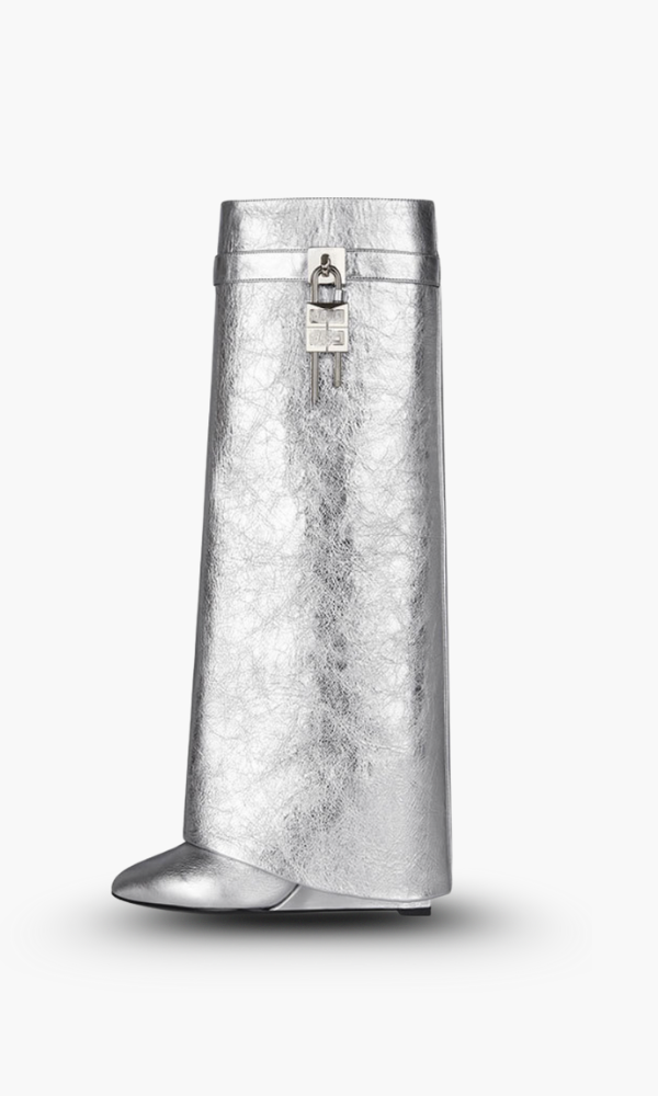 Dynamic shot of women's black glossy knee-high boots; sculptural wedge defines futuristic fashion.