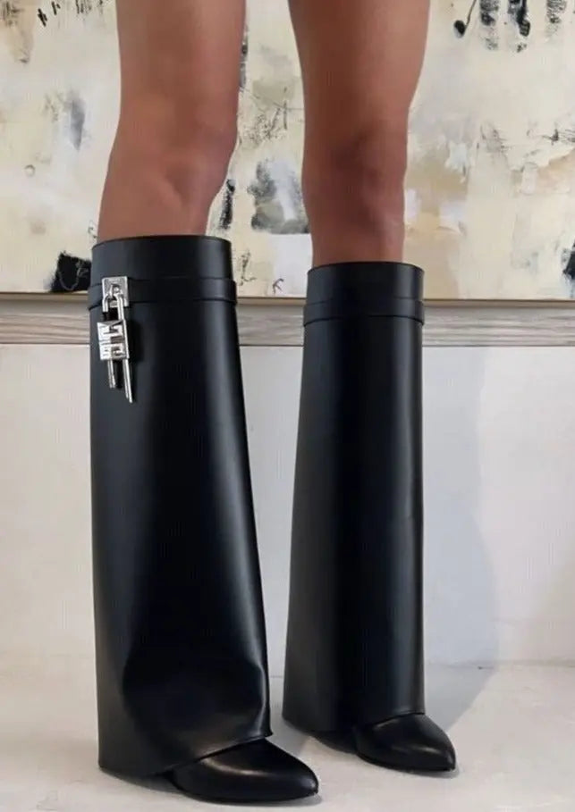 Women's fashion-forward black glossy boots; knee-high length, sculptural wedge, statement footwear.