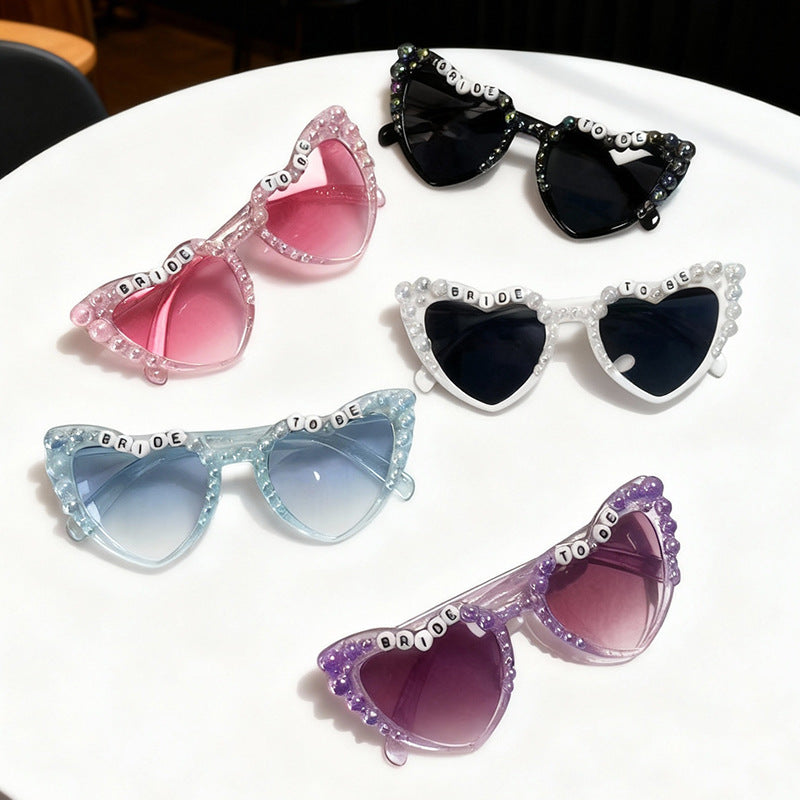 Stylish cat-eye bridal sunglasses for bachelorette parties. Pearl embellished, 'Bride To Be' party accessory. UV400 protection.