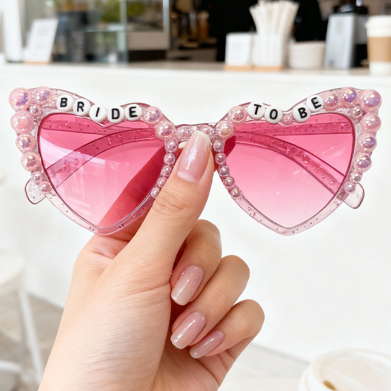 Trendy cat-eye bridal sunglasses with UV400 protection. Pearl-studded, perfect accessory for 'Bride To Be' bachelorette parties.