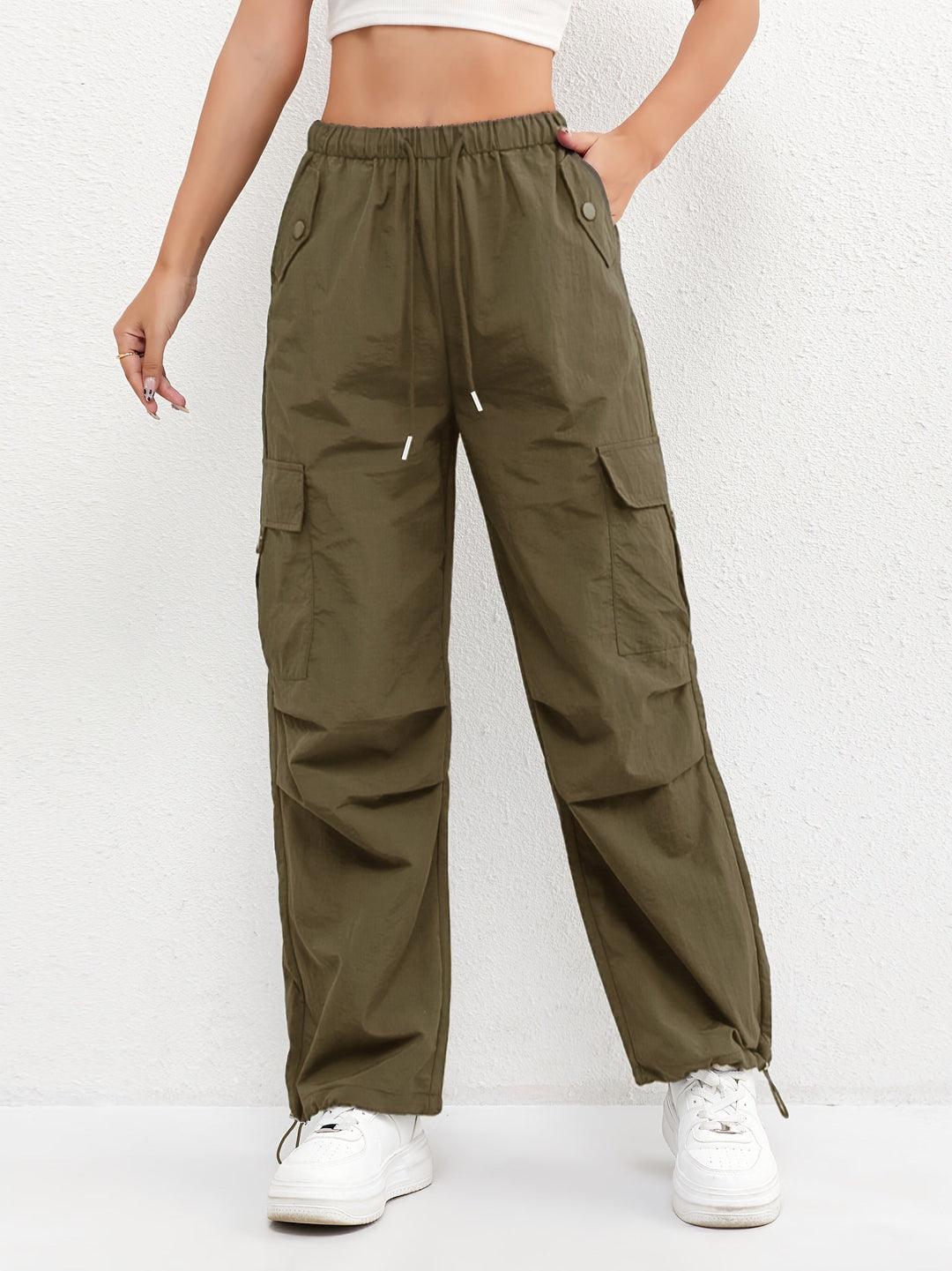 Close-up of women's cargo pants showing drawstring waist, functional flap pockets, and relaxed leg fit.