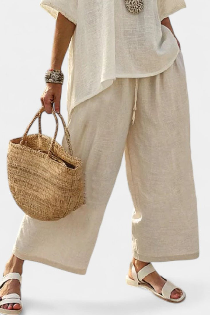 Fashionable women's summer co-ord set: elegant asymmetric top paired with flowing wide-leg trousers, ideal for resort.