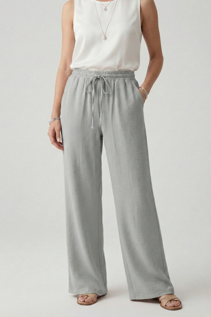 Woman walking in casual wide-leg palazzo trousers with drawstring waist & pockets, showcasing comfortable movement.